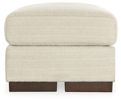 Ashley Furniture Maggie Ottoman featuring a soft fabric top and wooden legs, ideal for living room decor.