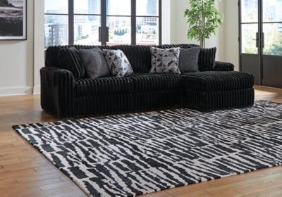 Ashley Furniture Midnight-Madness sectional sofa with chaise, dark fabric upholstery and modern design, shown in a stylish living room setting.