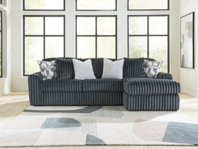 Ashley Furniture Midnight-Madness sectional sofa with chaise, featuring plush cushions and dark upholstery in a modern living room setting.