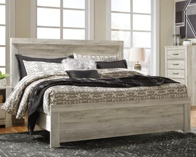 Ashley Furniture Bellaby Bed with a wooden frame and headboard, showcasing a modern design in a cozy bedroom setting.