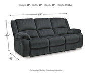 Ashley Furniture Draycoll reclining sofa with plush cushions and fabric upholstery, shown in a relaxed seating position.