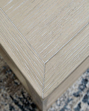 Ashley Furniture Marxhart end table with a wooden finish and modern design, shown in a contemporary living room setting.