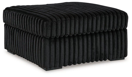Ashley Furniture Midnight-Madness oversized accent ottoman with plush fabric and modern design, shown in a cozy living room setting.