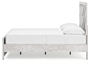 Ashley Furniture Cayboni Bed with beige upholstered headboard and wooden frame, shown from a side angle.