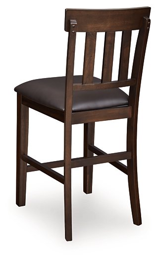 Ashley Furniture Haddigan counter height bar stool with wooden seat and backrest, featuring a sleek, modern design.